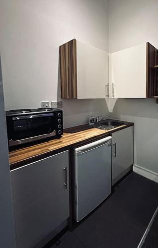 a small kitchen with a sink and a microwave at 5 STAR LUXURY STUDIO APARTMENT, BIG SMART TV, WiFI, LIVERPOOL CITY CENTRE, EASY ACCESS LOCK BOX ENTRY! in Liverpool