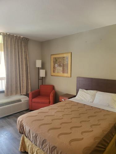 ein Hotelzimmer mit einem Bett und einem roten Stuhl in der Unterkunft Baymont by Wyndham Williamsburg in Williamsburg