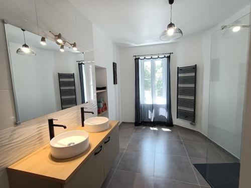 une salle de bain avec deux lavabos et un grand miroir dans l'établissement Maison de village en Provence, à Saint-Geniès-de-Comolas