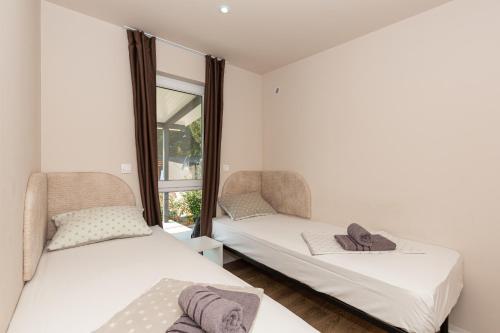Duas camas num quarto com uma janela em Mobile House KASTANJOLA em Biograd na Moru