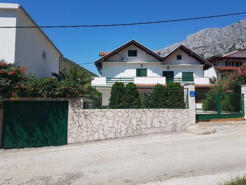 a white house with a stone wall and a fence at Sandra Apartmani 2 in Zaostrog