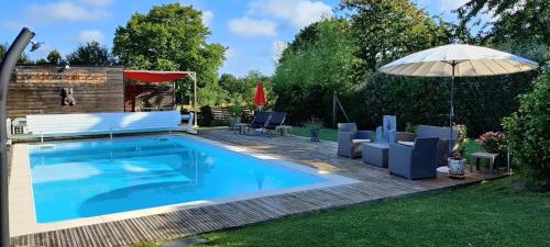 - une piscine dans une cour avec un parasol et des chaises dans l'établissement La maison du Lac, à Éguzon-Chantôme