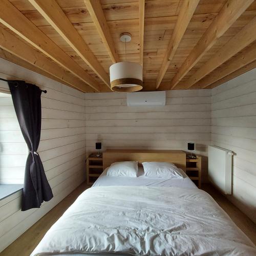 a bed in a room with a wooden ceiling at Au Charm'Han in Han-sur-Lesse