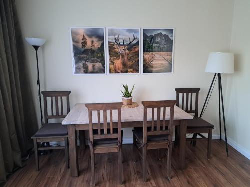 a dining room table and chairs with three pictures on the wall at Apartament Natura in Lidzbark Warmiński