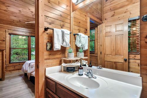 baño con lavabo blanco y paredes de madera en Stay and Play at The Ryland: Private Game Room & Community Pool Retreat en Gatlinburg