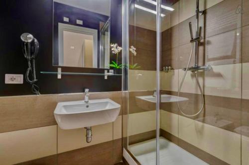 uma casa de banho com um lavatório e uma cabina de duche em vidro. em DGS APARTHOTEL em Trapani