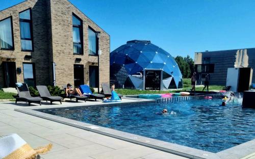 a group of people in a swimming pool next to a building at Makin' Memories - Apartamentai Monciškėse in Palanga