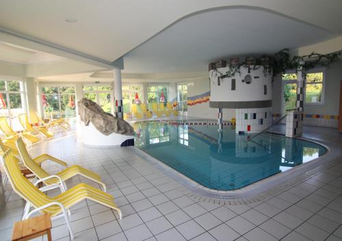 uma grande piscina com cadeiras amarelas e uma piscina em Wohlfühl Hotel Wiesenhof em Grafendorf bei Hartberg