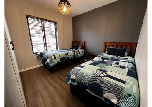 1 dormitorio con 2 camas y ventana en Mo's Explorer Cape Town Vacation Apartment, en Ciudad del Cabo