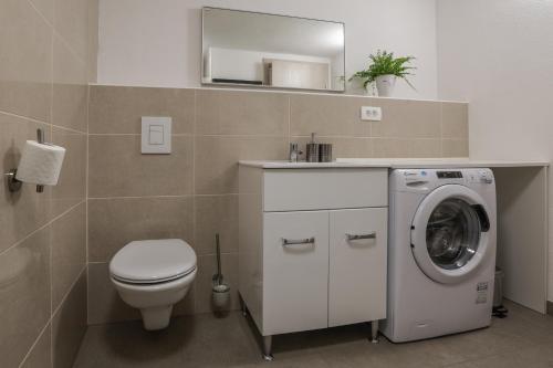 a bathroom with a toilet and a washing machine at Apartment For You in Bled