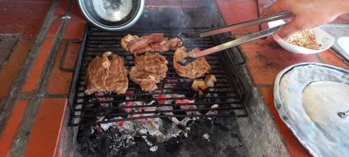 a person is cooking meat on a grill at Finca Campestre Villa Carilina in Curití
