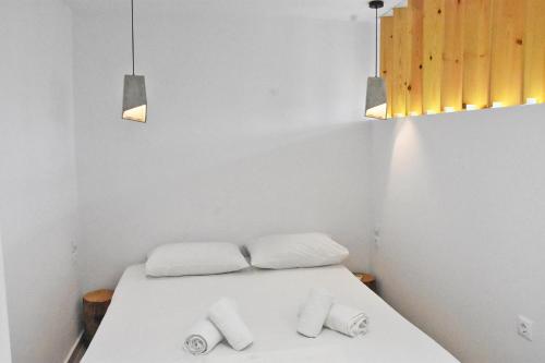 a white room with a bed with two towels at MNS Marvelous Nirvana Seascape, Philosophy in Panayía