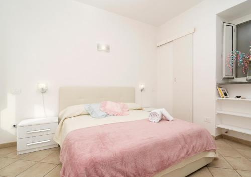 a white bedroom with a bed with a pink blanket at Casetta Lucia in Massa Lubrense