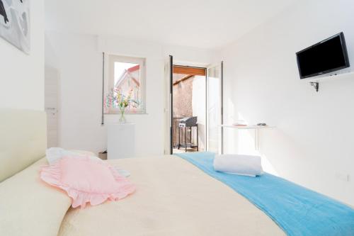 een witte kamer met een bed met roze en blauwe lakens bij Casetta Lucia in Massa Lubrense