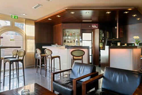 a bar with leather chairs and a counter in a restaurant at Hotel Conti Dietikon in Dietikon