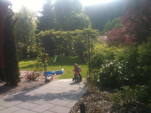 a child sitting on a bike in a garden at Hotel Restaurant L Echo du Lac in Gérardmer