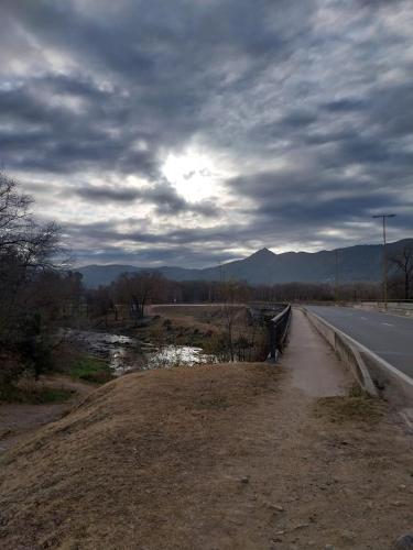 a dirt road next to a road with a cloudy sky at Complejo majua in Cosquín