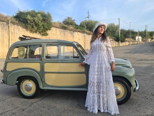 a woman in a white dress standing next to a car at Novecento Room and Breakfast Puglia in Massafra