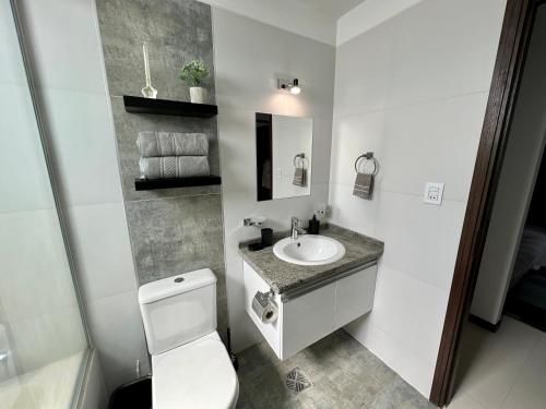a white bathroom with a toilet and a sink at Acogedor departamento en el corazón de cochabamba in Cochabamba
