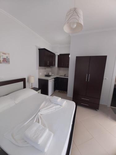 a bedroom with a white bed and a kitchen at MyKsamil Apartments in Ksamil