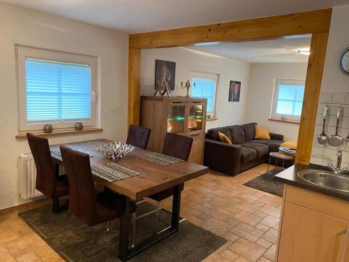eine Küche und ein Wohnzimmer mit einem Tisch und einem Sofa in der Unterkunft Waldheimat - Ferienhaus Nürburg in Nürburg