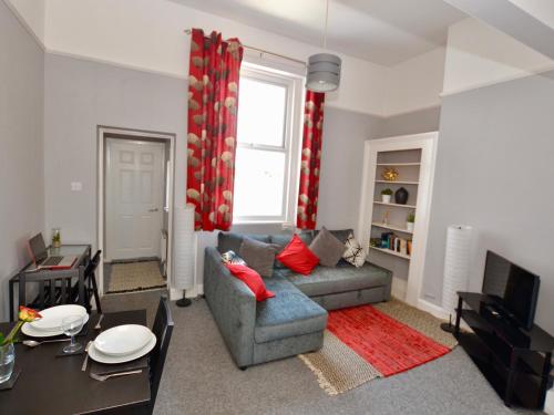 een woonkamer met een bank en een tafel bij Stephen's Cheltenham apartment in Cheltenham