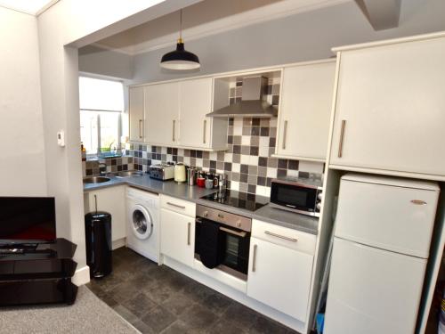 a kitchen with white cabinets and a dishwasher at Stephen's Cheltenham apartment in Cheltenham