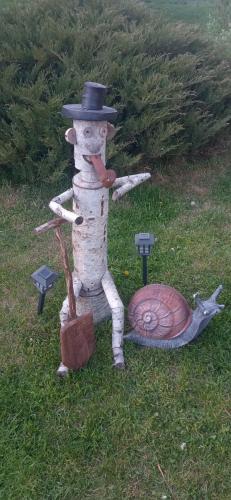 a scarecrow with a hat and a snail on the grass at Domek na Mazurach Leśne Zacisze in Ostaszewo