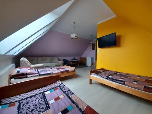 sala de estar con 2 camas y pared amarilla en Dom Gościnny u Szymona, en Wrzosowo