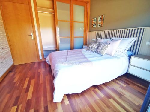1 dormitorio con 1 cama blanca grande y suelo de madera en Exclusivo atico en Salvaterra, en Salvatierra de Miño