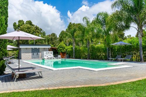 uma piscina com duas cadeiras e um guarda-sol em Casale Delle Ronde B&B em Latina