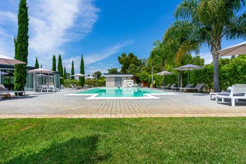 a swimming pool in a yard with chairs and umbrellas at Casale Delle Ronde B&B in Latina