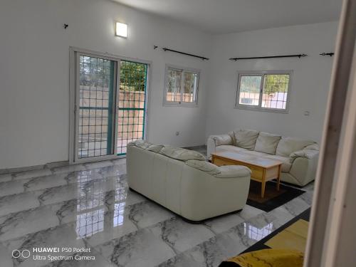 sala de estar con sofás, mesa y ventanas en SWEET HOME YENNE, en Rufisque