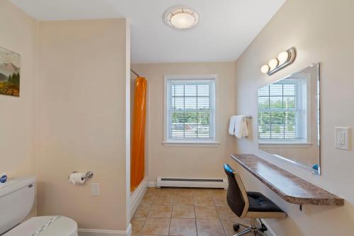 a bathroom with a sink and a toilet and two windows at Wagon Wheel Motel in Saco