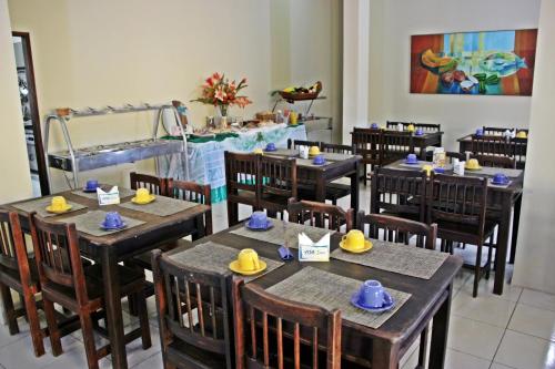 ein Restaurant mit Holztischen und Stühlen mit Hüten darauf in der Unterkunft Pousada Vila do Porto in Porto De Galinhas