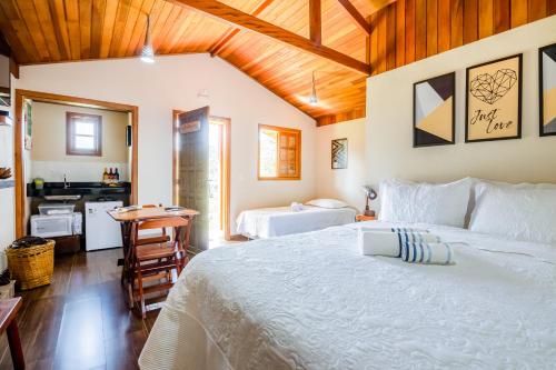 a bedroom with a large white bed and a kitchen at Chalés Terra dos Sonhos - Monte Verde in Monte Verde
