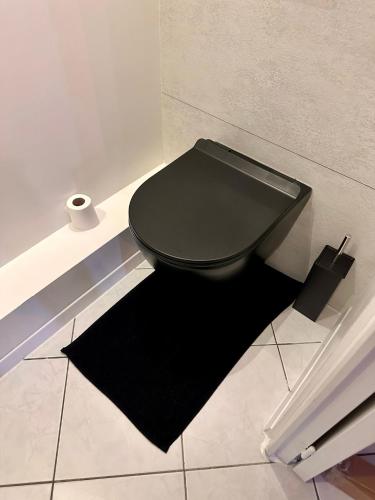 a black toilet in a bathroom with a black rug at Le Tropical sublime ambiance Jungle proche Metz in Noisseville