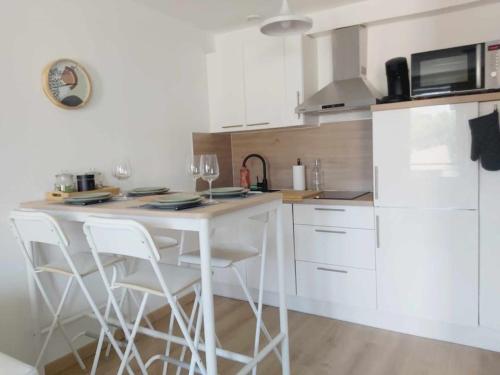 a kitchen with white cabinets and a white table and chairs at Les Coteaux de Mahé in Tournon-sur-Rhône