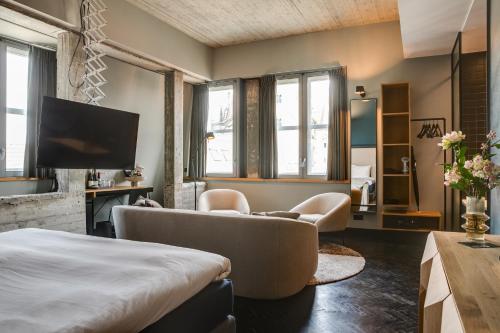 a room with a bed and a couch and a tv at The Duke Boutique Hotel in Den Bosch
