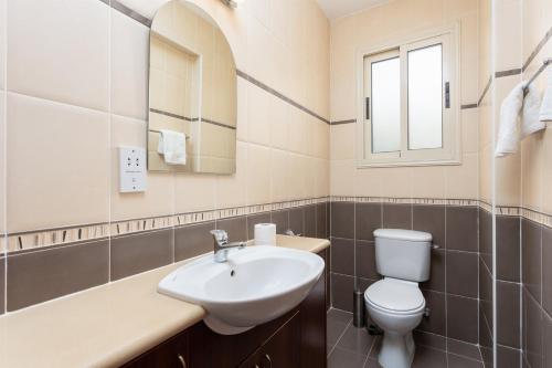 W łazience znajduje się umywalka, toaleta i lustro. w obiekcie Villa Galina w mieście Neo Chorio
