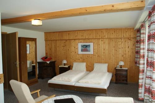 a bedroom with a bed and a wooden wall at Hotel Pension Spycher in Kandersteg