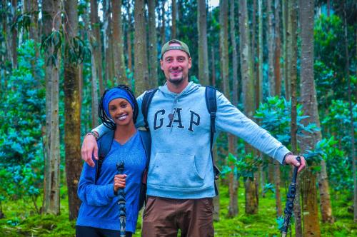 a man and a woman standing in a forest at Volcanoes Over View Safaris & Camp in Nyarugina