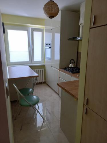 a kitchen with a table and a green chair at Apartament 7 Piętro in Bydgoszcz