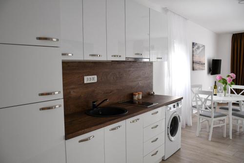 a kitchen with white cabinets and a sink and a dishwasher at Raj in Kotor