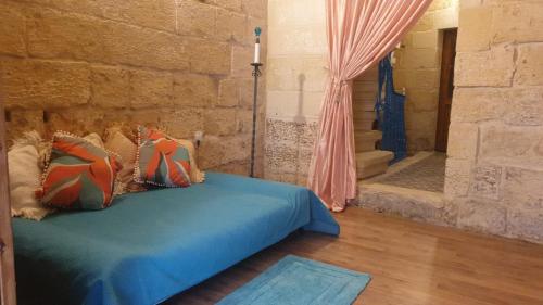 a bedroom with a bed and a stone wall at Tifkira (The Memory) in Birgu