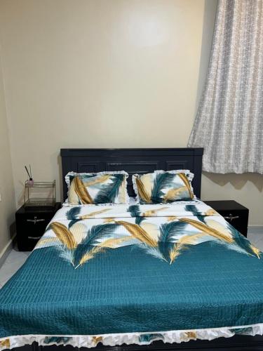 a bed with a blue comforter and pillows at Cozy Haven furnished apartments in Kampala