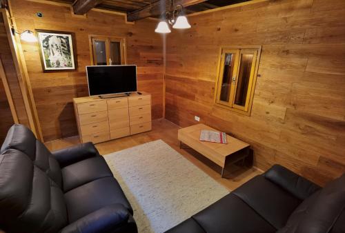 a living room with a couch and a tv at Mountain Hut Stara Hiša in Kupjak