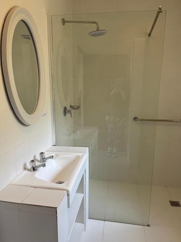 a white bathroom with a sink and a shower at Hermanus Heights Villa in Hermanus