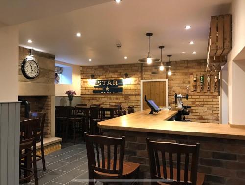 a bar in a restaurant with a clock on the wall at The Star Inn - Harbottle - Near Rothbury - Northumberland in Morpeth