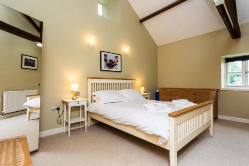 a bedroom with a large white bed and a window at Cheviot Barn in Chatton